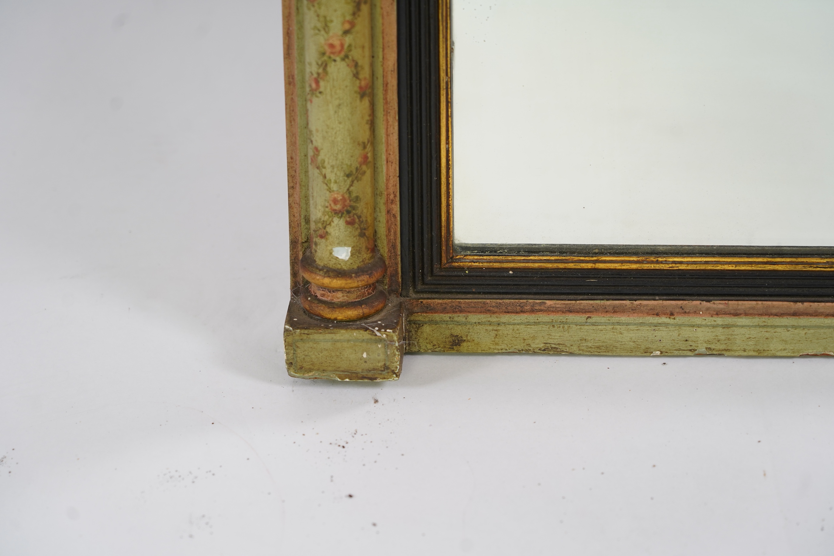 A Regency giltwood and composition overmantel mirror, with verre eglomise tablet frieze depicting a castle facade over a rectangular plate with reeded ebonised slip flanked by turned floral painted projecting columns, wi